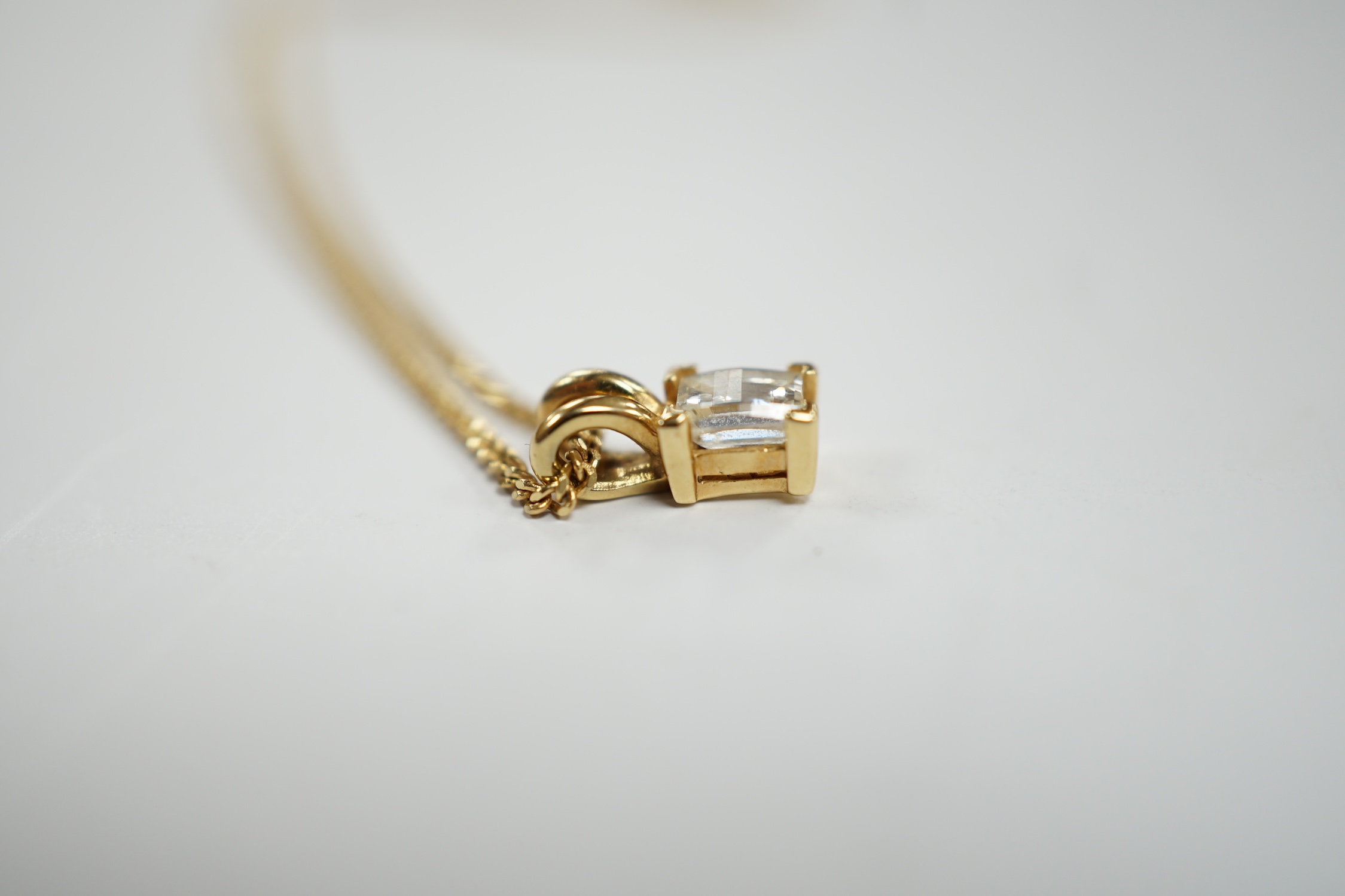 A modern 18ct gold and single stone fancy rectangular cut diamond set pendant, 9mm, on an 18ct gold fine link chain, 46cm, gross weight 3.6 grams.